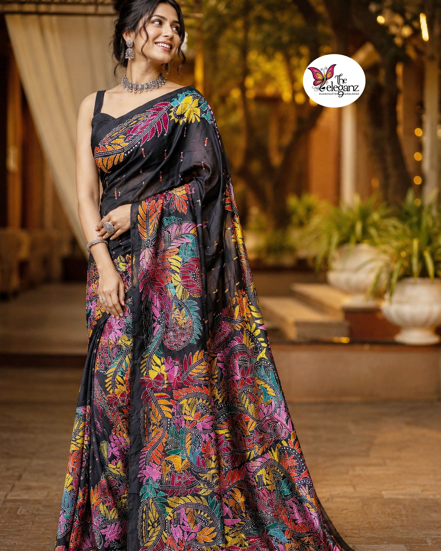 Woman draped in a black blended Bangalore silk saree featuring colourful Padma Kantha embroidery with lotus flowers, vines, and traditional Bengali motifs