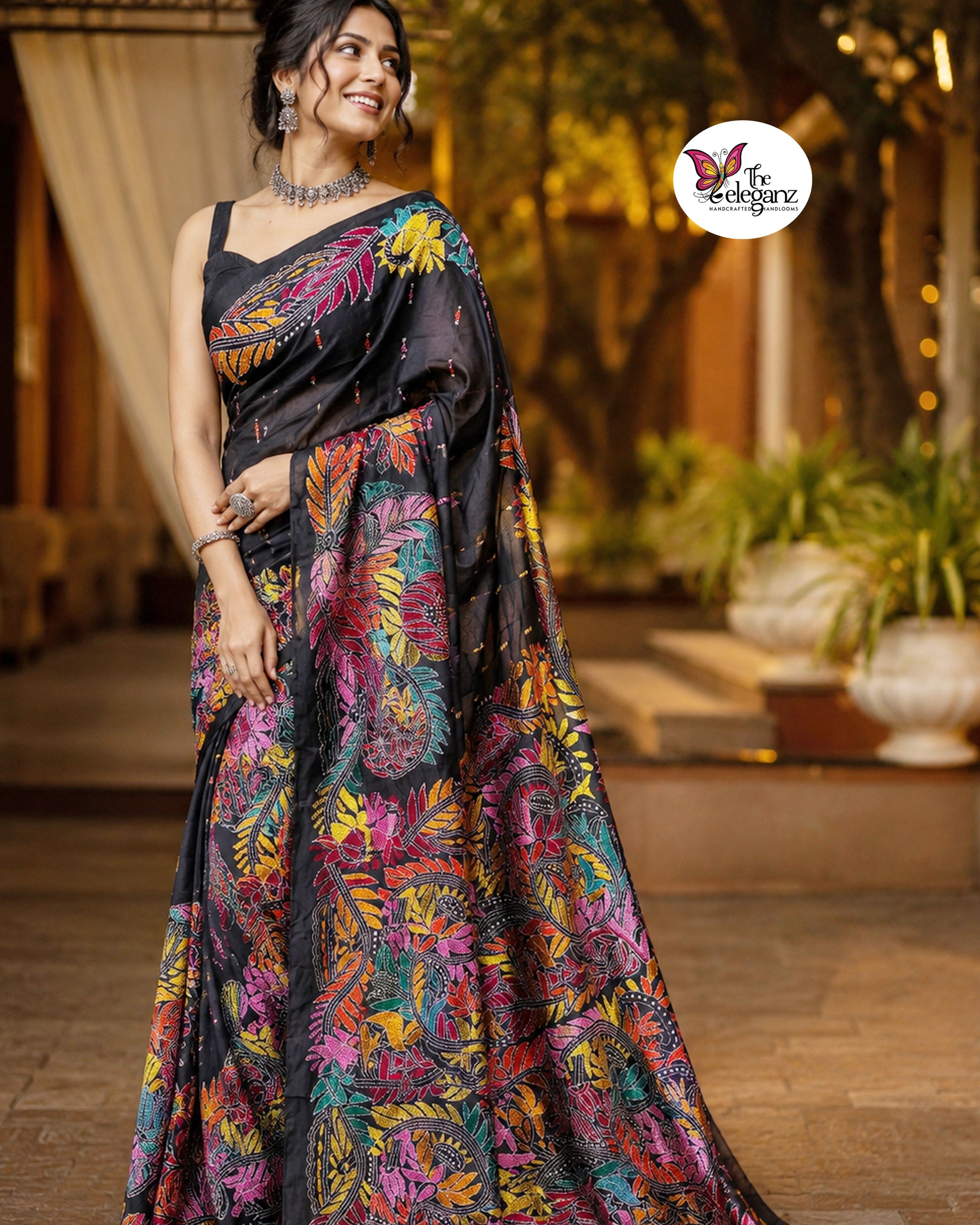 Woman draped in a black blended Bangalore silk saree featuring colourful Padma Kantha embroidery with lotus flowers, vines, and traditional Bengali motifs