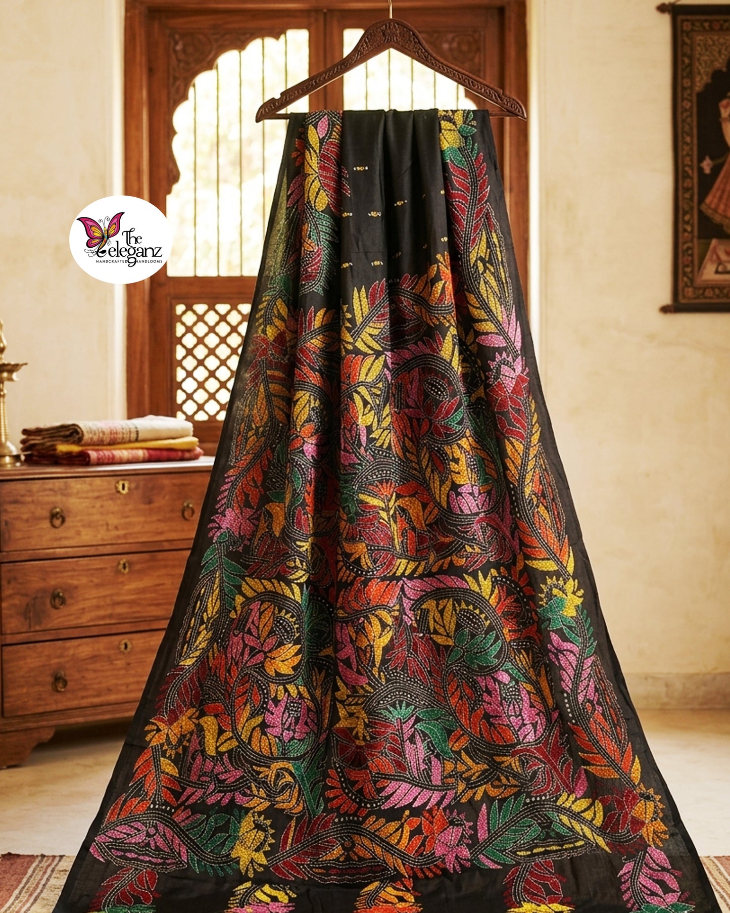 Woman draped in a black blended Bangalore silk saree featuring colourful Padma Kantha embroidery with lotus flowers, vines, and traditional Bengali motifs