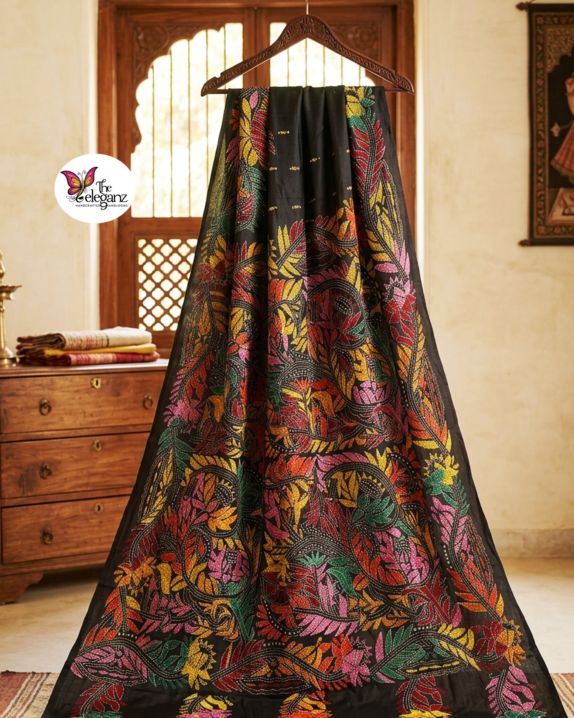 Woman draped in a black blended Bangalore silk saree featuring colourful Padma Kantha embroidery with lotus flowers, vines, and traditional Bengali motifs