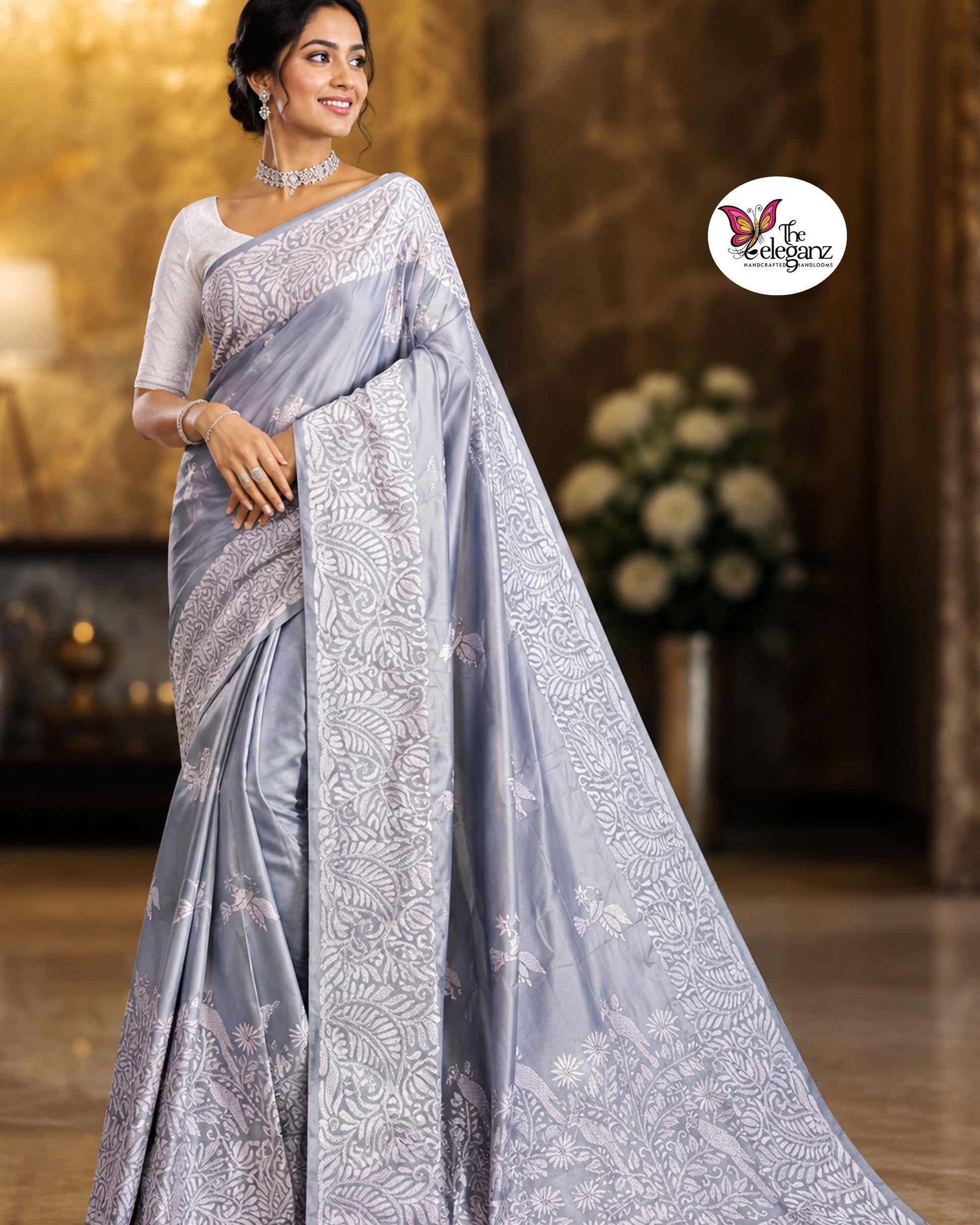 Woman draped in a steel grey blended Bangalore silk saree featuring intricate white Kantha embroidery with bird, floral, and foliage motifs across the border and pallu.