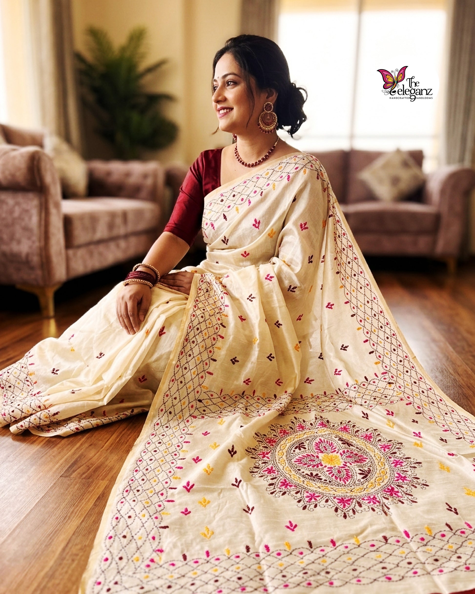 Woman draped in an ivory white embroidered semi silk saree featuring multicolour floral motifs, geometric borders, and an ornate embroidered pallu design.