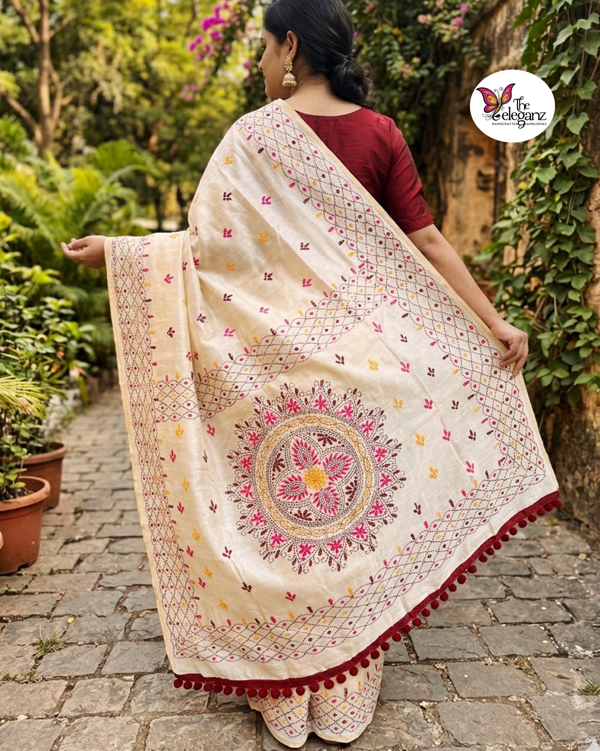 Woman draped in an ivory white embroidered semi silk saree featuring multicolour floral motifs, geometric borders, and an ornate embroidered pallu design.