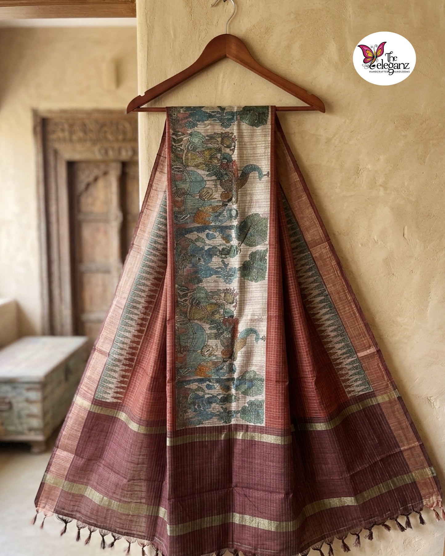 Woman draped in a checked maroon semi tussar silk saree featuring heritage-inspired print work with peacock, royal, and folk-art motifs on the pallu.