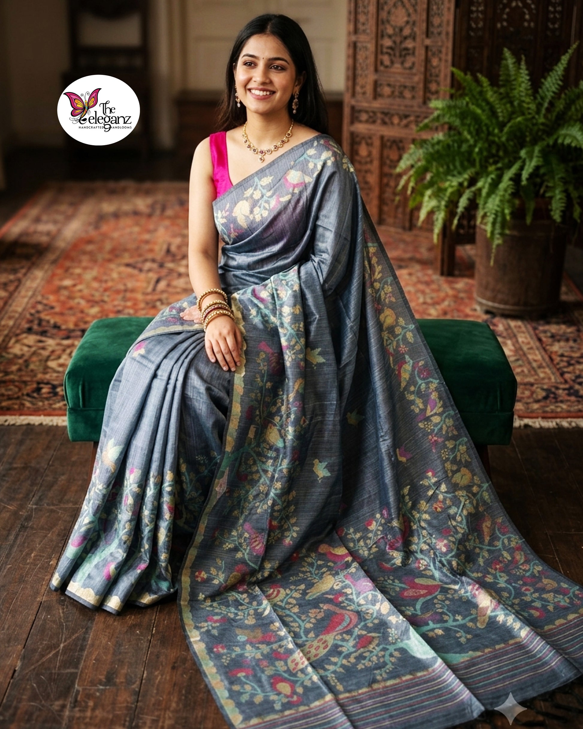 Woman draped in a smoky grey semi tussar silk saree featuring woven bird, floral, and vine motifs across the border and pallu with matching blouse piece.