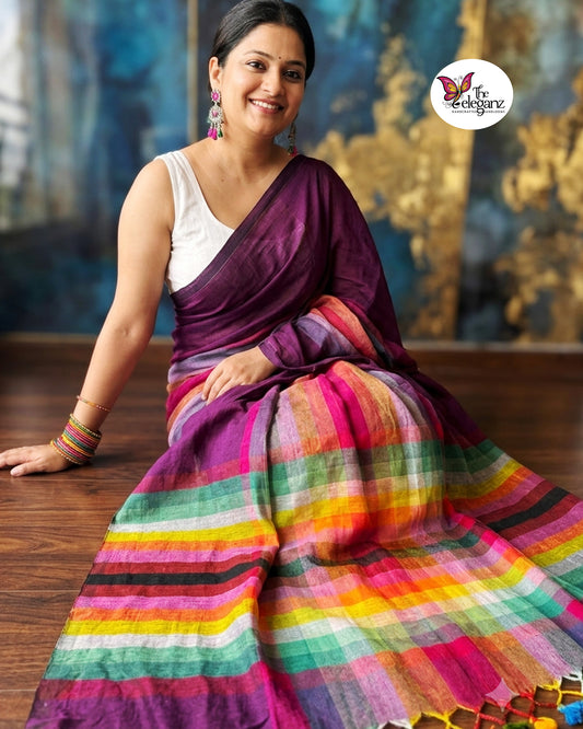 Woman wearing a plum purple Mul Cotton saree featuring colourful checked pallu, multicolour woven detailing, and handcrafted tassels.