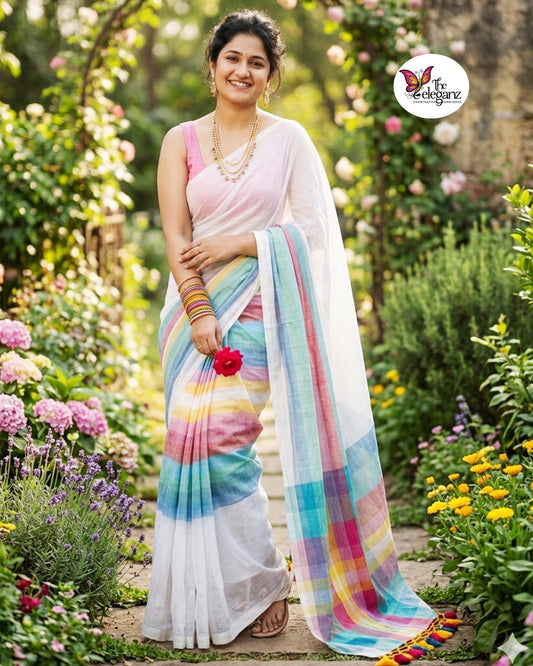 Woman draped in a white Mul Cotton saree featuring pastel multicolour striped border and pallu with colourful handcrafted tassels.