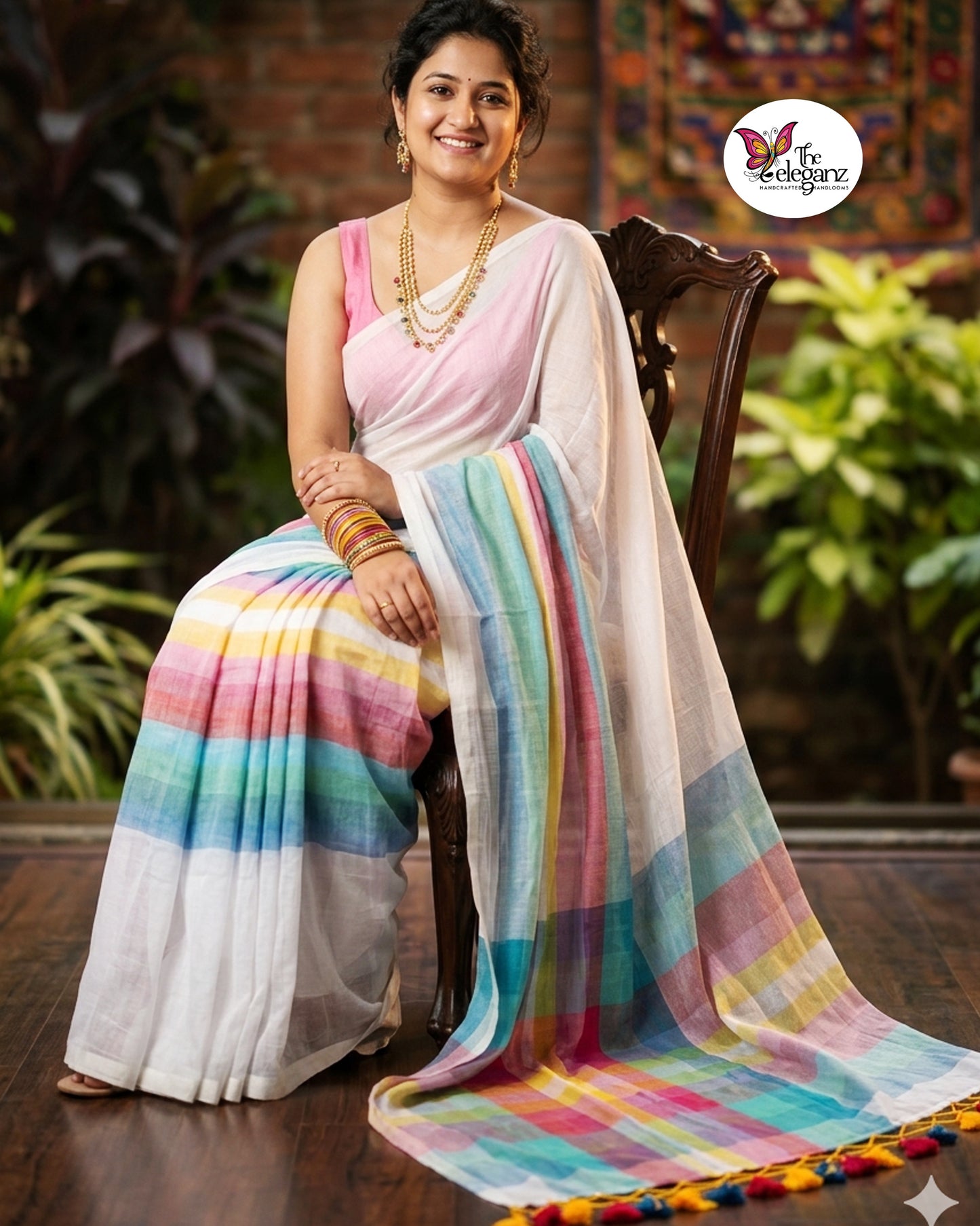 Woman draped in a white Mul Cotton saree featuring pastel multicolour striped border and pallu with colourful handcrafted tassels.