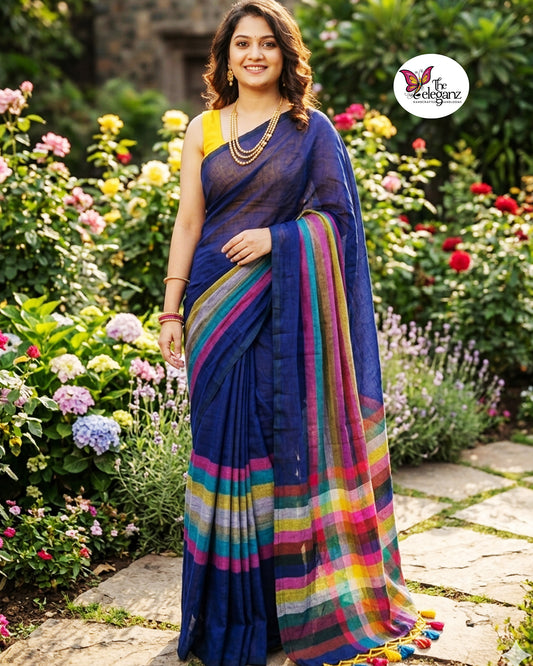 Woman draped in an indigo blue Mul Cotton saree featuring vibrant multicolour striped border and pallu with colourful handcrafted tassels.