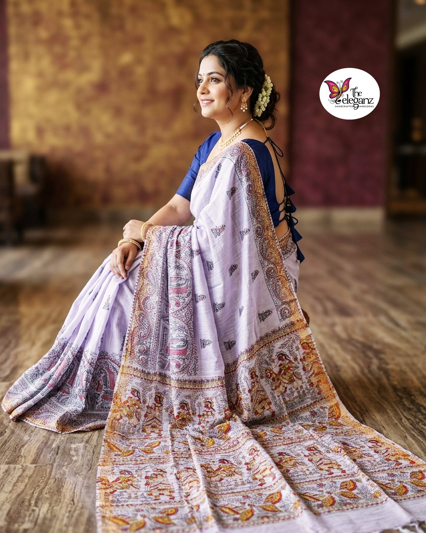 Woman draped in lavender Cotton Silk Madhubani saree featuring traditional folk art figures, paisley motifs, and intricate heritage-inspired decorative borders.